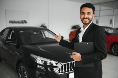 indian cheerful car salesman at showroom