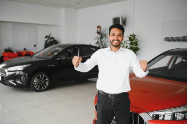A young Indian man chooses a new car at a car dealership.