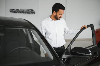 A young Indian man chooses a new car at a car dealership.