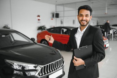 indian cheerful car salesman at showroom
