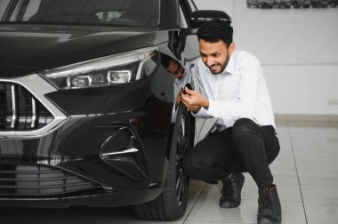 A young Indian man chooses a new car at a car dealership.