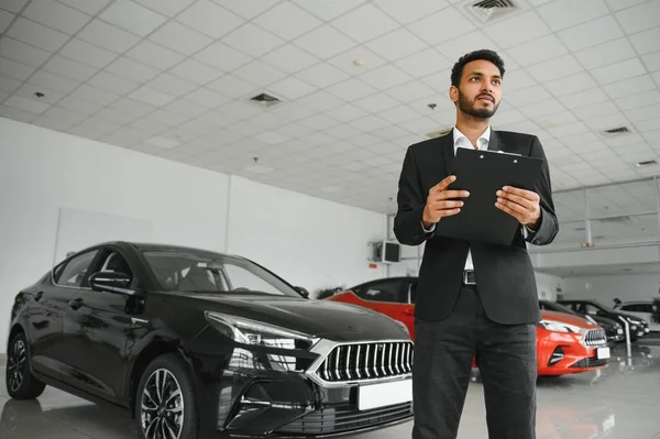 Successful indian businessman in a car dealership - sale of vehicles to customers