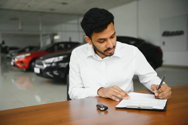 Young Indian Man Signing Documents Car Dealership — ストック写真