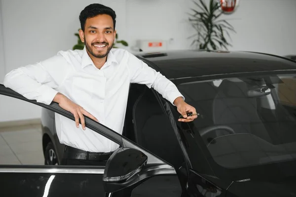 stock image A young Indian man chooses a new car at a car dealership.