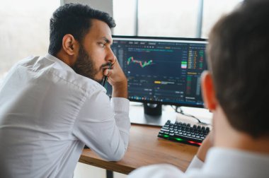 Akıllı Hintli kripto tüccarı, yatırımcı, analist bilgisayar ve akıllı telefon kullanarak dijital kripto döviz borsasını, borsa grafiklerini, yatırım yapmayı düşünme ve fon risklerini analiz ediyor.