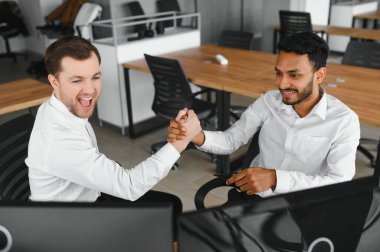 Two successful trader sitting in office and looking at screen, checking cryptocurrency information data on finance market graph, pointing on monitor.