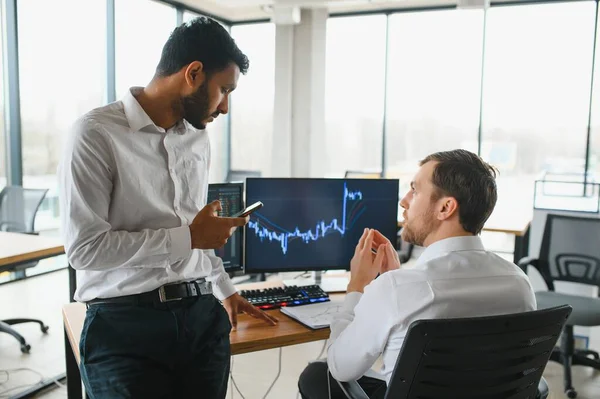 stock image Two men traders sitting at desk at office together monitoring stocks data candle charts on screen analyzing price flow smiling cheerful having profit teamwork concept.