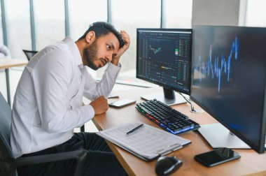 Portrait of a positive successful Indian or Arabian trader, stock market broker, Crypto charts on laptop screen.