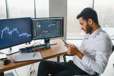 Portrait of a positive successful Indian or Arabian trader, stock market broker, Crypto charts on laptop screen.