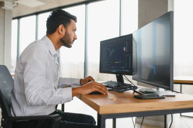 Pozitif başarılı bir Hintli veya Arap tüccarın portresi, borsa simsarı, dizüstü bilgisayardaki kripto çizelgeleri.
