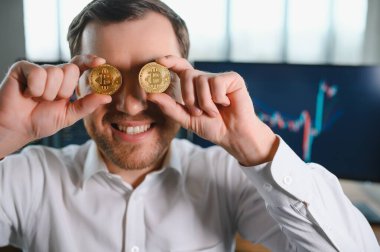 trader holding bitcoin coins on his face.