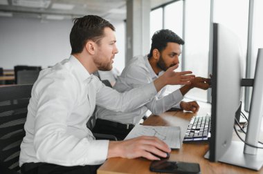 Ofiste oturan ve ekrana bakan iki başarılı tüccar, finans piyasası grafiğindeki kripto para birimi verilerini kontrol ediyor, monitöre işaret ediyor..