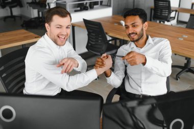 Two men traders sitting at desk at office together monitoring stocks data candle charts on screen analyzing price flow smiling cheerful having profit teamwork concept.