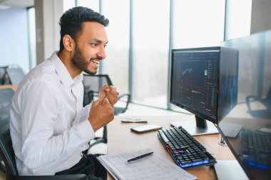 Portrait of a positive successful Indian or Arabian trader, stock market broker, Crypto charts on laptop screen.