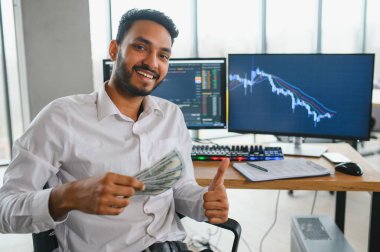 Portrait of a positive successful Indian or Arabian trader, stock market broker, Crypto charts on laptop screen.