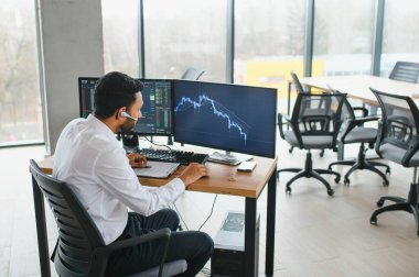 Portrait of a positive successful Indian or Arabian trader, stock market broker, Crypto charts on laptop screen.