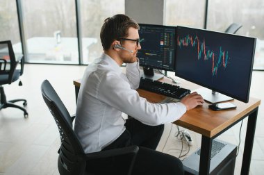 Successful and concentrated trader in formalwear looking at monitor, analyzing global bitcoin price on network diagram, working in office.