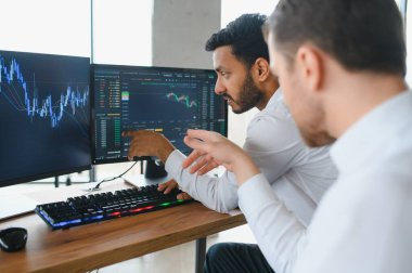 Two men traders sitting at desk at office together looking at data analysis discussing brainstorming successful strategy inspired teamwork concept close-up.