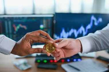 View of hand holding a bitcoin and giving it to other people. Cryptocurrency trading concept.