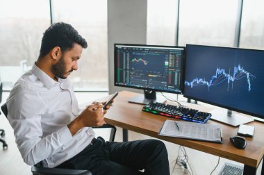 Düşünceli, konsantre Hintli iş adamı yatırımcı yönetici bilgisayar kullanıyor, web sitesinde veri pazarını analiz ediyor ve dizüstü bilgisayara bakarak web araştırması yapıyor.