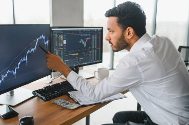 Portrait of a positive successful Indian or Arabian trader, stock market broker, Crypto charts on laptop screen.