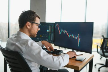 Successful trader in formalwear checking cryptocurrency information data on finance market graph, working in office.