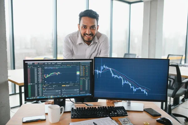 stock image Portrait of a positive successful Indian or Arabian trader, stock market broker, Crypto charts on laptop screen.