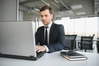 Genç yakışıklı işadamı dizüstü bilgisayar ekranında bağırmak ve mali durumu hakkında rakip yetenekleri, istemci ihtiyaçlarını karşılamak mümkün kıskanç kızgın modern ofis masasında çalışan vurguladı.