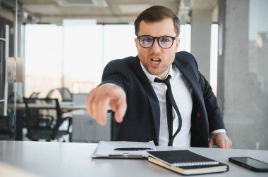 Angry businessman sitting at the table and screaming