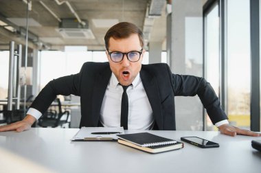 Angry businessman sitting at the table and screaming