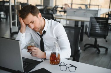 İş adamı iş yerinde stresten su içiyor.