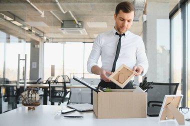 Hüzünlü Kovma. Ofis çalışanı eşyalarını karton kutuya koyup ofisten ayrılmasına izin ver. İşgücü azaltma, küçültme, yeniden yapılanma, yeniden yapılanma, dış kaynak kullanımı. Kitle İşsizlik Piyasası Krizi.