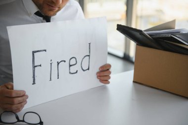 fired employee holding fired sign in hand.
