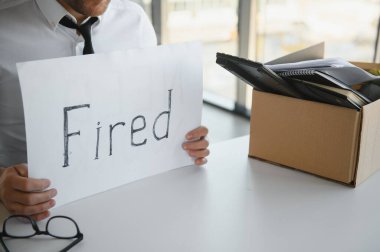 fired employee holding fired sign in hand.