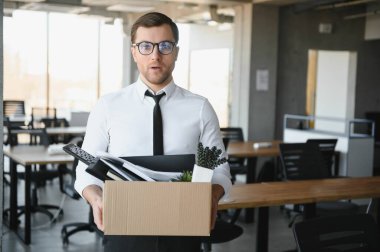 Hüzünlü Kovma. Ofis çalışanı eşyalarını karton kutuya koyup ofisten ayrılmasına izin ver. İşgücü azaltma, küçültme, yeniden yapılanma, yeniden yapılanma, dış kaynak kullanımı. Kitle İşsizlik Piyasası Krizi.