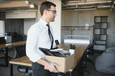 Sad Fired. Let Go Office Worker Packs His Belongings into Cardboard Box and Leaves Office. Workforce Reduction, Downsizing, Reorganization, Restructuring, Outsourcing. Mass Unemployment Market Crisis.