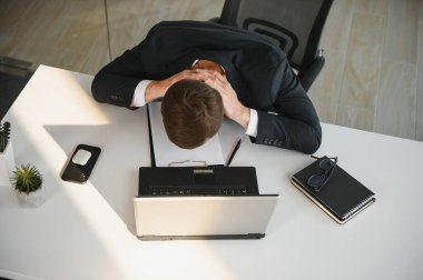 Depresyondaki genç iş adamının el ele tutuşması, sorunu var, masada bir dizüstü bilgisayar. Adamın biri bir işte hata yapmış..