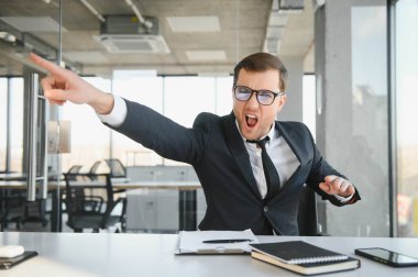 Angry businessman sitting at the table and screaming