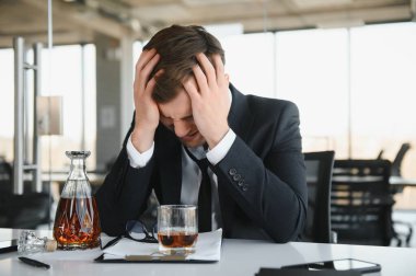 Alcoholism at work. Tired employee drinking alcohol at workplace, can not handle stress
