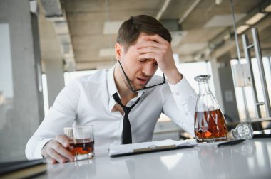 Alcoholism at work. Tired employee drinking alcohol at workplace, can not handle stress