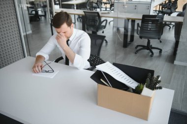 Sad Fired. Let Go Office Worker Packs His Belongings into Cardboard Box and Leaves Office. Workforce Reduction, Downsizing, Reorganization, Restructuring, Outsourcing. Mass Unemployment Market Crisis.