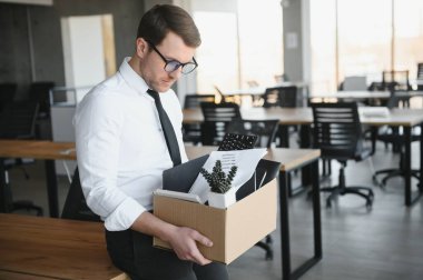 Sad Fired. Let Go Office Worker Packs His Belongings into Cardboard Box and Leaves Office. Workforce Reduction, Downsizing, Reorganization, Restructuring, Outsourcing. Mass Unemployment Market Crisis.