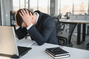 Depresyondaki genç iş adamının el ele tutuşması, sorunu var, masada bir dizüstü bilgisayar. Adamın biri bir işte hata yapmış..