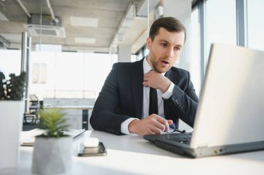 Genç yakışıklı işadamı dizüstü bilgisayar ekranında bağırmak ve mali durumu hakkında rakip yetenekleri, istemci ihtiyaçlarını karşılamak mümkün kıskanç kızgın modern ofis masasında çalışan vurguladı.