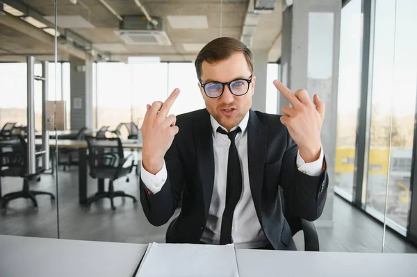 Portrait of angry business man showing double middle fingers.