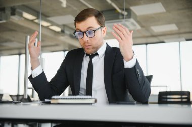 Angry businessman sitting at the table and screaming