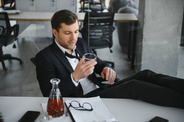 Alcoholism at work. Tired employee drinking alcohol at workplace, can not handle stress