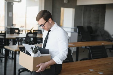 Hüzünlü Kovma. Ofis çalışanı eşyalarını karton kutuya koyup ofisten ayrılmasına izin ver. İşgücü azaltma, küçültme, yeniden yapılanma, yeniden yapılanma, dış kaynak kullanımı. Kitle İşsizlik Piyasası Krizi.