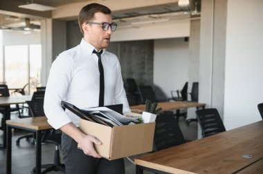 Genç yakışıklı işadamı karton kutu ışık modern ofiste. Son günün. Üzgün ofis çalışanı işten
