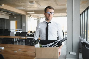 Sad Fired. Let Go Office Worker Packs His Belongings into Cardboard Box and Leaves Office. Workforce Reduction, Downsizing, Reorganization, Restructuring, Outsourcing. Mass Unemployment Market Crisis.